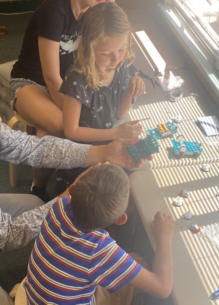 Two students looking at simple circuit board to make a toy car.